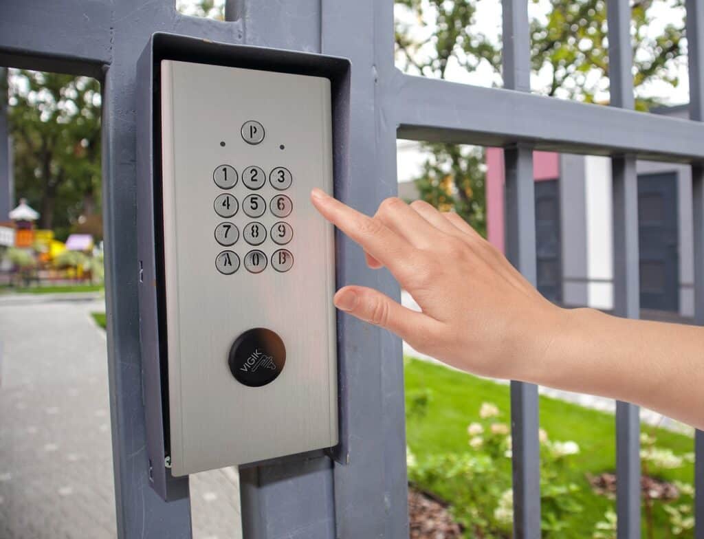 une main qui s'apprête à appuyer sur les boutons d'un interphone à clavier